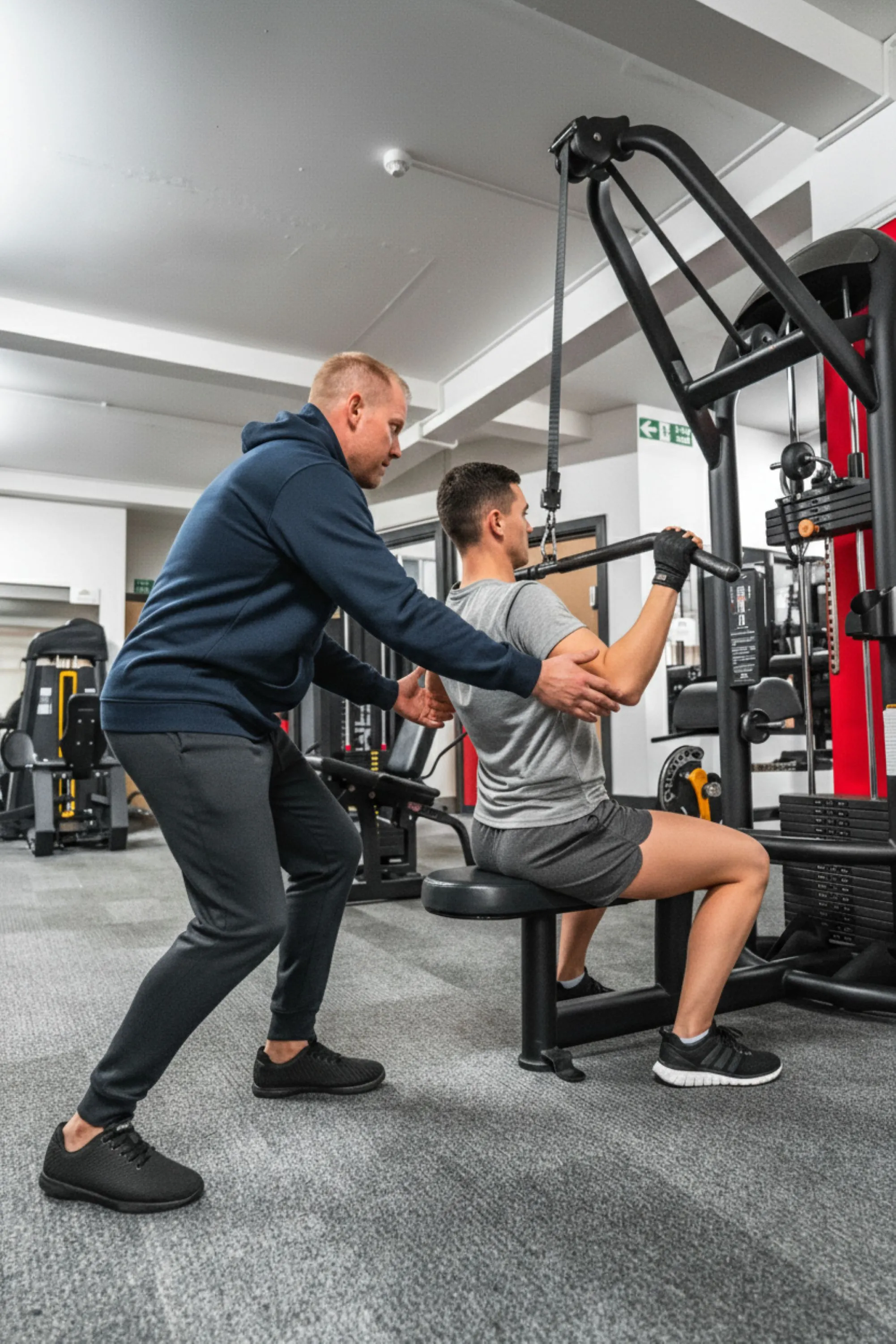 Personal trainer membimbing klien saat latihan menggunakan alat cable machine di gym